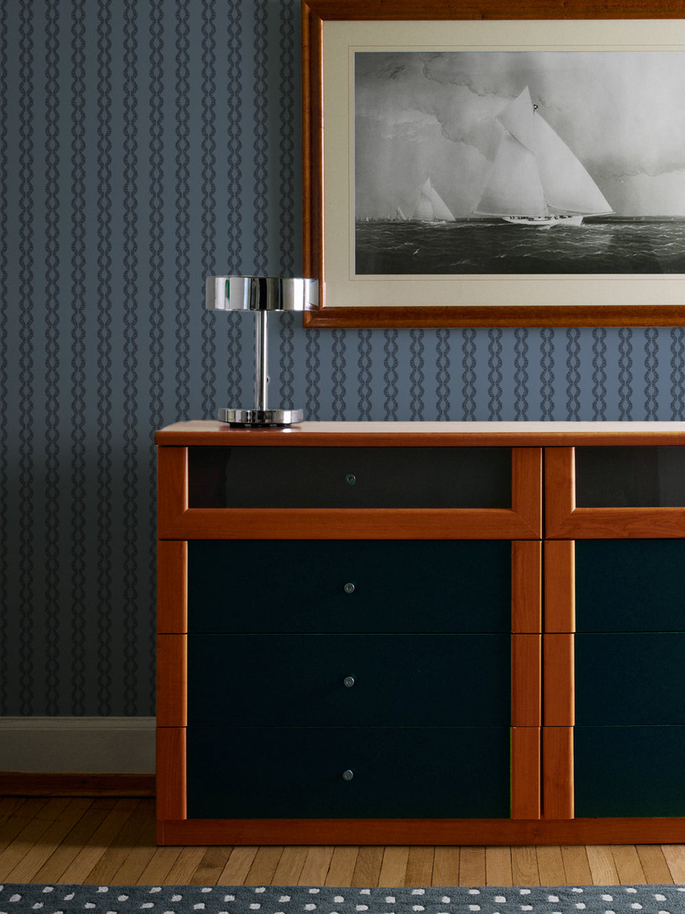 Vintage Navy Sutton Vine wall above a teal and wood dresser with chrome table lamp and sailboat print