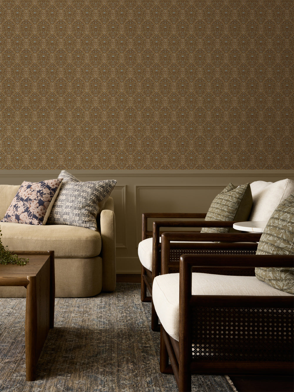 Tan and brown Taliah wallpaper above panelled wainscot with a beige sofa and cane armchairs