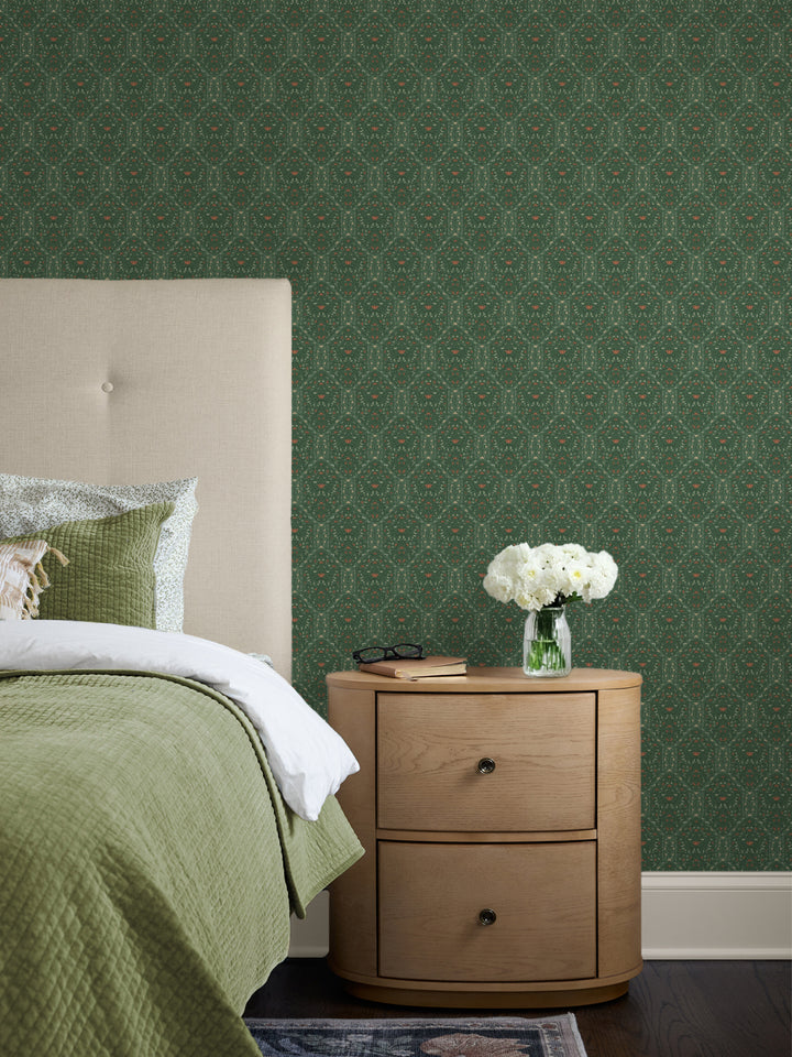 Green Taliah wallpaper behind a cream headboard, sage quilt, oak nightstand and white peonies