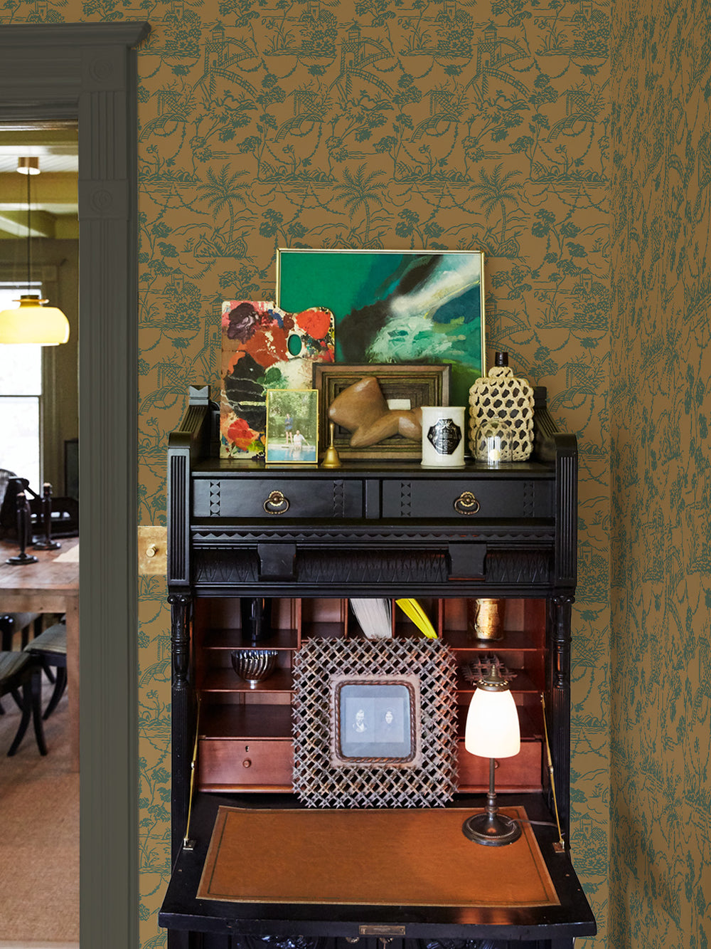 Jungle toile wallpaper covering an accent wall behind a console table; teal pattern on tan.
